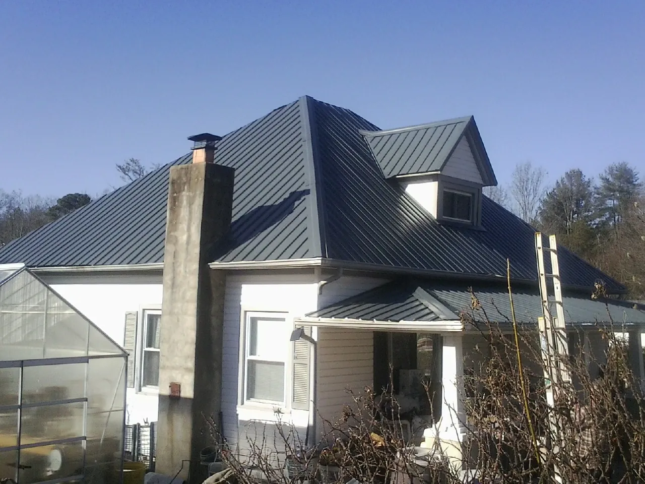 Dark blue standing seam metal roof on a white farmhouse with dormer — Slate & Tile Roof Repair by Roofing Brothers in Hoffman Estates