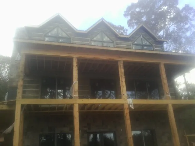 Dormers and porch framing on a large log home under construction — Roof Coating work by our crew in Hoffman Estates
