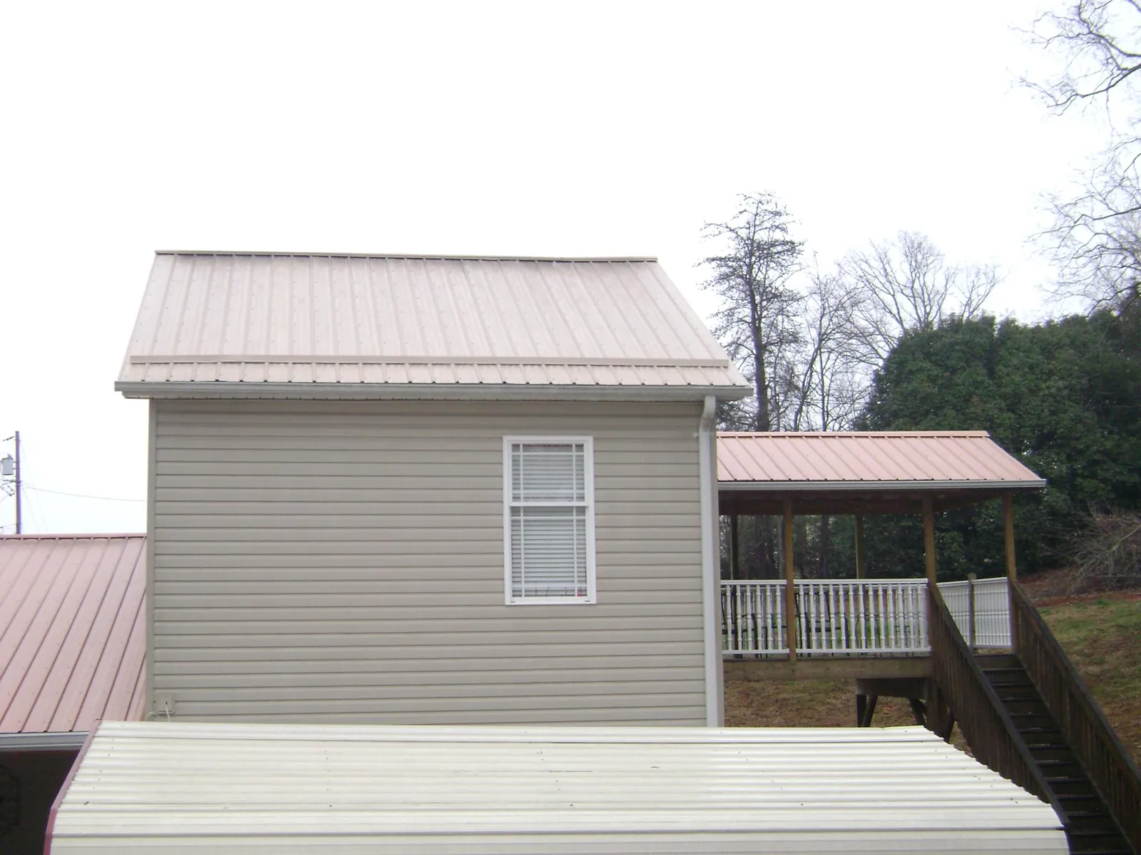 Tan metal roofs on a two story addition and attached porch, from a Roof Replacement job in Hoffman Estates